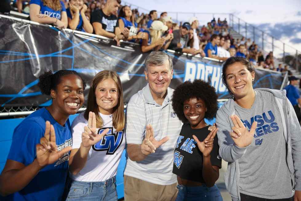 President Haas with students at football game, holding anchor up signs
